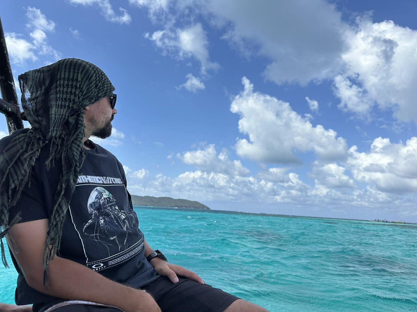 Patrice Bouffard assis à l'avant d'un bateau, regardant l'eau turquoise au large de Roatán